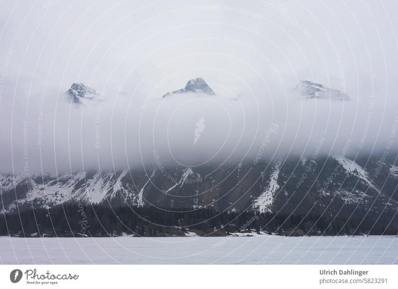 three mountain peaks rise out of a cloud bank in a winter landscape mountains Winter Clouds Fog chill Snow Higher Engadin icily White Winter mood Cold Frost