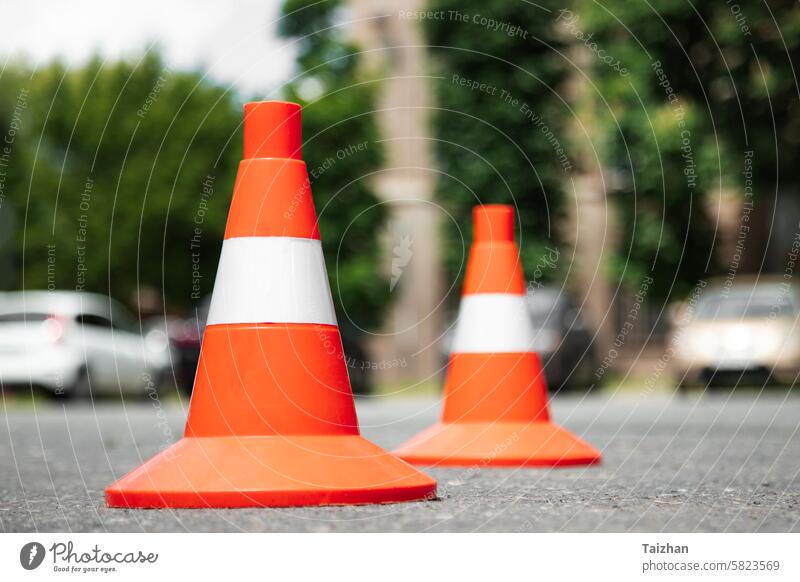 Bright red orange traffic cones standing in a row on  an asphalt in the city. Low angle view . Close up background boundary car caution center color image