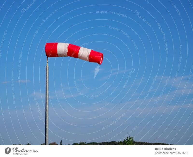 Rot-weiss gestreifter Windsack flattert fast vollständig aufgebläht vor blauem Himmel sommer Sommerurlaub windig Meer strand Urlaub Nordsee Ostsee Ferien Natur