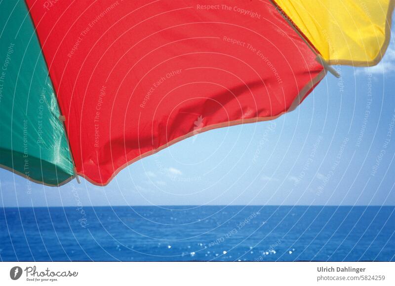 Detail of a parasol in bright green/red/yellow in front of a blue sea and blue sky Summer Sun ardor Shadow voyage Ocean vacation holidays relaxation Beach