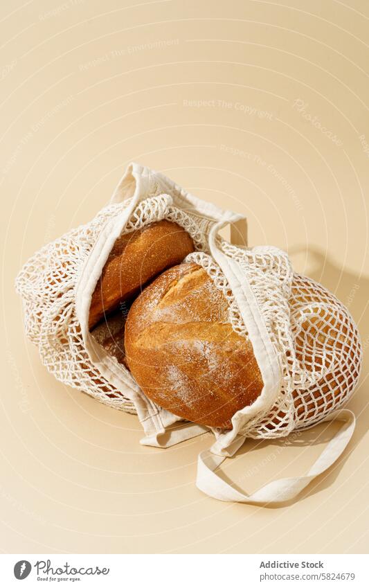 Fresh sourdough breads in a reusable bag on beige eco-friendly background baking artisanal loaf crusty fresh woven alternative packaging zero waste sustainable