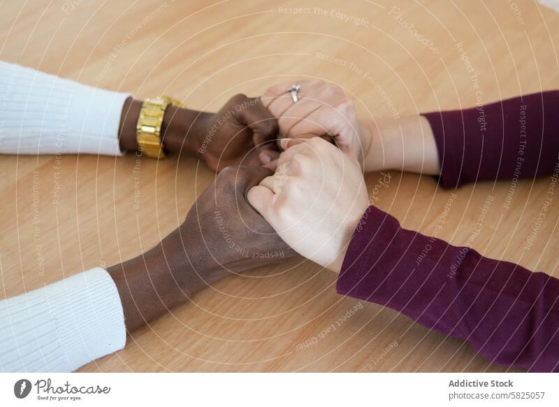 Diverse group of people joining hands on table teamwork unity support diversity together cooperation collaboration community wooden table close-up multiethnic