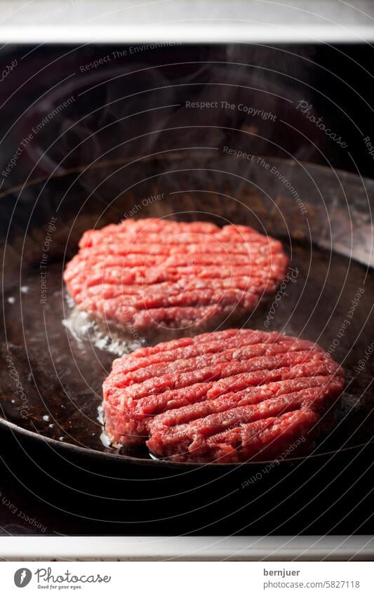 Two beef patties in an iron skillet Patty two Beef Patties Iron Pan Food boil nobody Slice burger Minced meat Raw Milled preparation hacked BBQ Fat Red Smoke