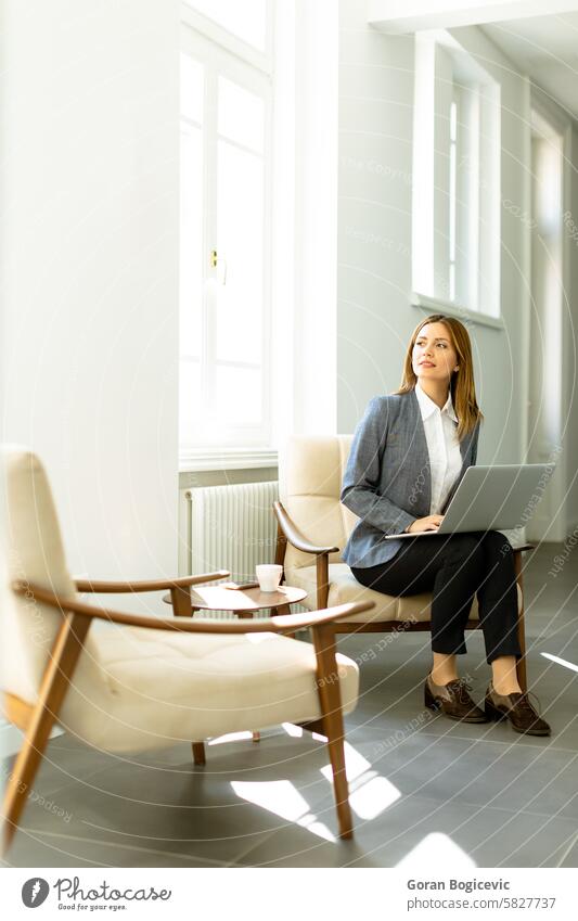 Serene afternoon at work: a professional woman focuses intently on her laptop in a sunlit room working sunlight bench business casual office technology serene