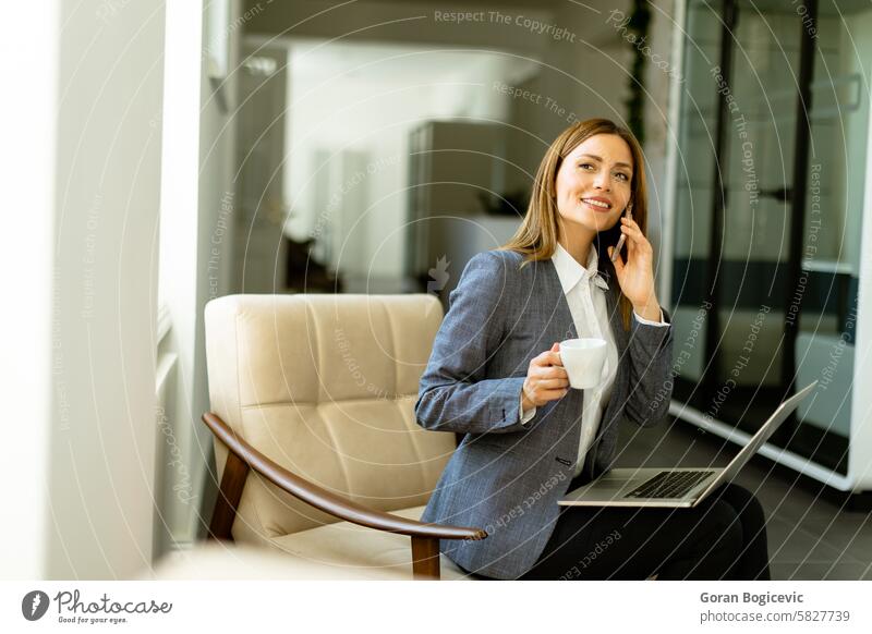 Elegant professional woman engaged in a business call with morning coffee attire phone laptop conversation office technology wireless communication multitasking