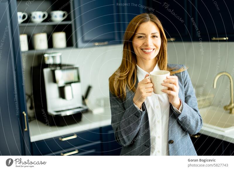 Confident Businesswoman Enjoying a Coffee Break in a Modern Office Kitchen businesswoman coffee break smiling holding mug relaxing stylish blue professional