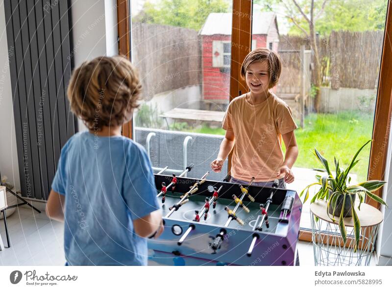 Two boys play table football at home active brothers cheerful child childhood children competition cute domestic life family friends fun game goal kids playing