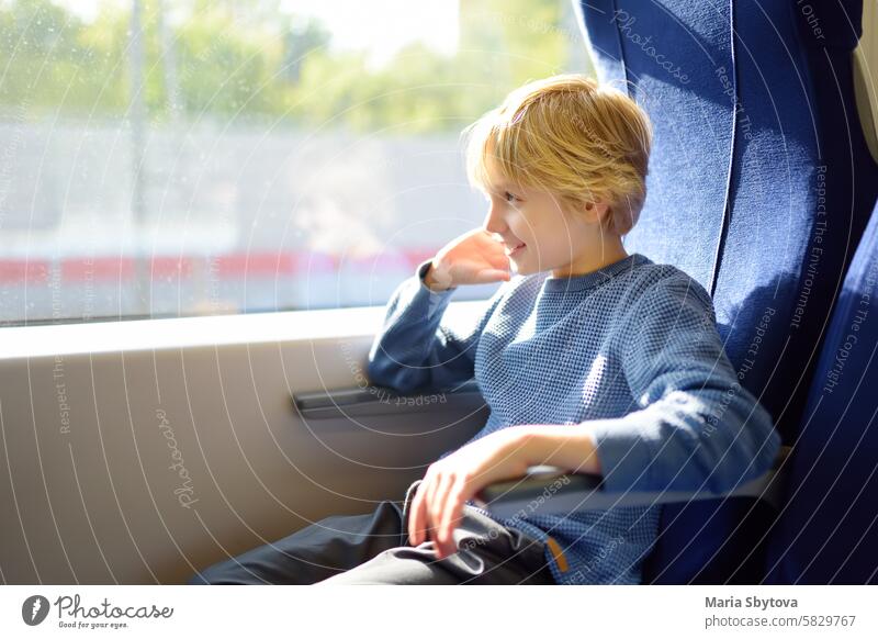 Cute preteen boy is traveling in a local train carriage or by railroad while it rain outside. suburban ride child fast city comfortable card seat Caucasian