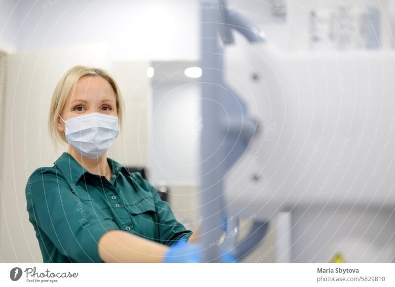 Female technician adjusts X-Ray machine. Female radiologist is going to take an Xray of patient in X-ray room of modern clinic. radiography doctor radiology