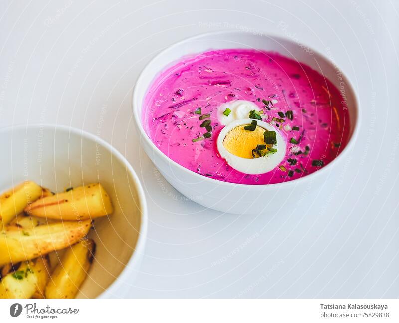 A plate with traditional Lithuanian cold summer soup of beetroot and kefir Saltibarsciai or Lithuanian kholodnik or cold borscht with baked potato wedges