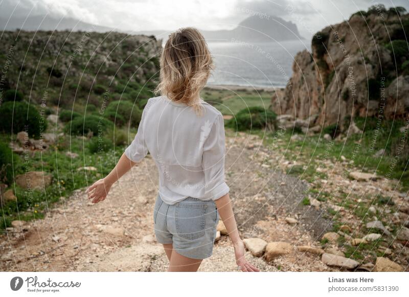 A gorgeous blonde girl is here to explore and be inspired by the majestic views of Sicily. The great outdoors in San Vito Lo Capo opens her eyes. The rough terrain, mountains, and moody sky recharge her batteries.