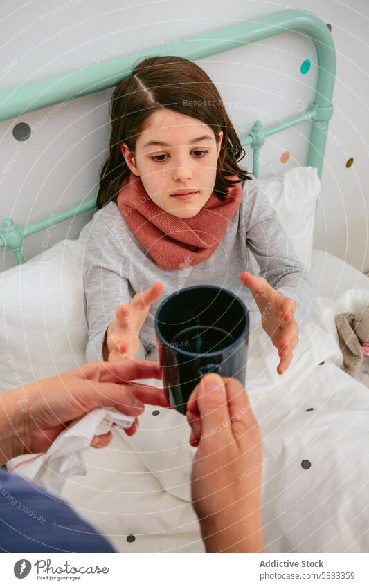 Young girl looking at a cup in a cozy bedroom setting scarf child attentive observing adult hand offer comfort pastel care indoor health morning routine