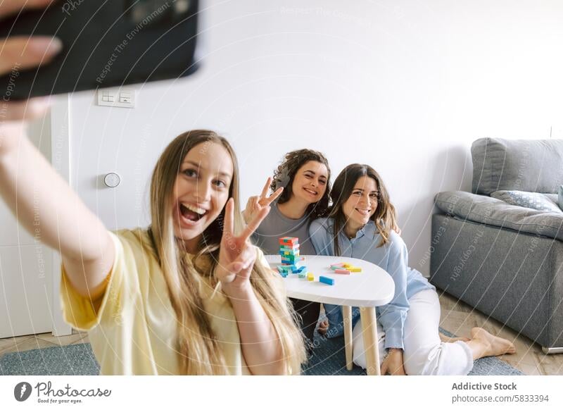 Friends Taking Selfie During Game Night at Home friend home play drink good time female camera selfie peace sign smile casual indoors game gathering social