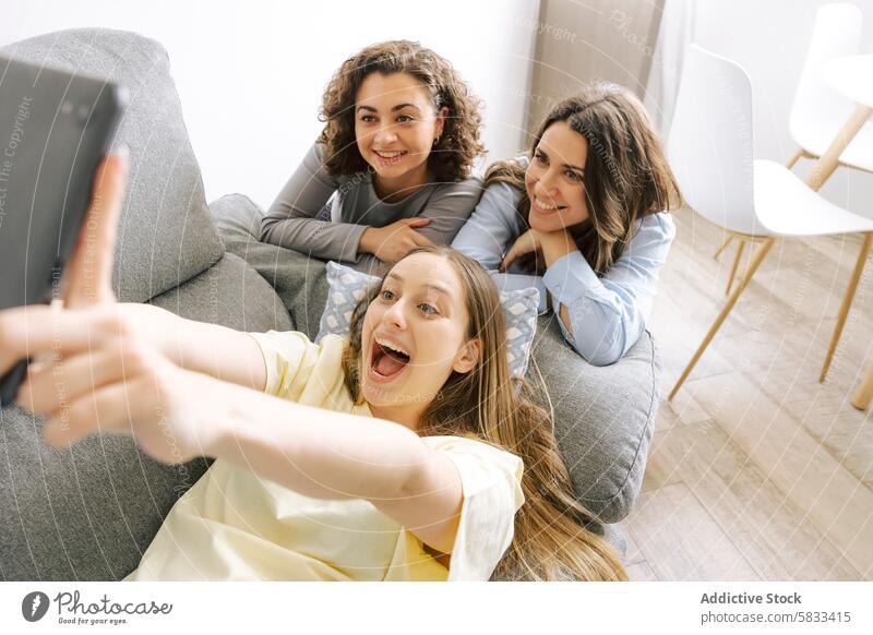 Friends Enjoying a Cozy Home Gathering friend home playing drinking good time gender women selfie couch smiling having fun indoor casual gathering togetherness