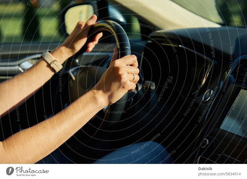 Inside view of woman driving car on countryside road driver steering wheel travel hand sunset dashboard vehicle journey transport day evening female interior