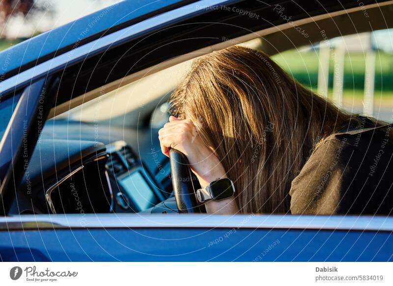 Woman is seated inside car with her head resting on steering wheel woman depression driving emotional bored driver sadness mental health problem daytime female