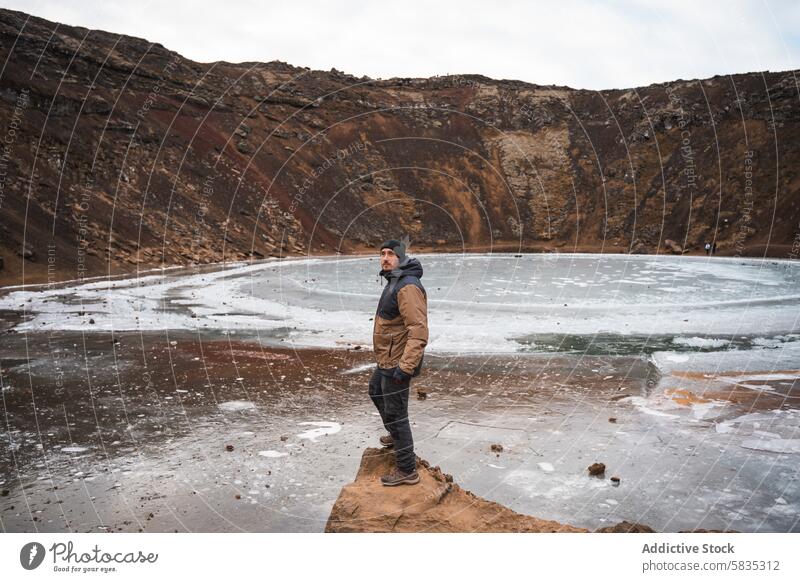 Man standing at a frozen volcanic crater in Iceland man traveler iceland snaefellsnes peninsula winter solitude landscape nature exploration cold rugged rocky
