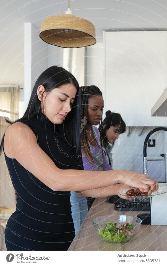 Three women cooking together in a modern kitchen woman salad teamwork ingredient healthy eating meal preparation contemporary diverse group collaboration focus