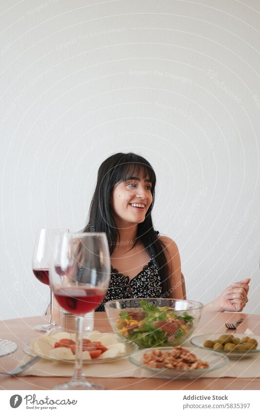 Young woman enjoying a meal with a glass of wine dinner table healthy food salad olive cheerful smile sit young adult casual dining eating indoors freshness