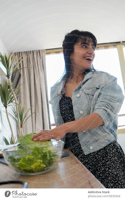 Smiling woman preparing salad in her kitchen cooking smiling happiness healthy casual home domestic life joy enthusiasm nutrition meal preparation fresh green