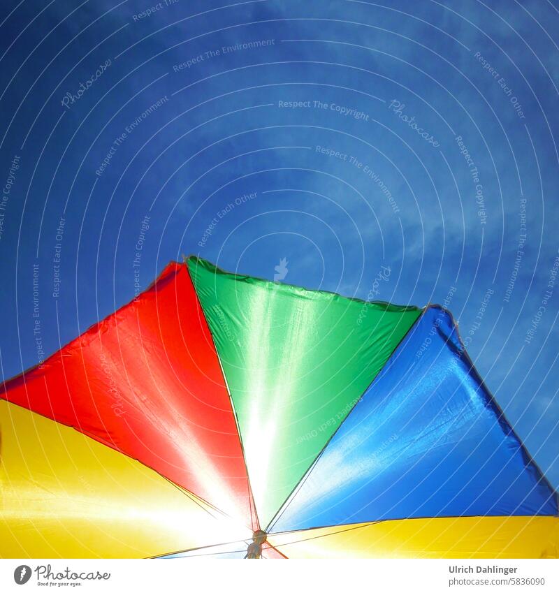 Parasol with red,yellow,green and blue segments in front of a blue sky.intense colors Summer Sun Shadow vacation holidays Sunlight Beautiful weather sunshine