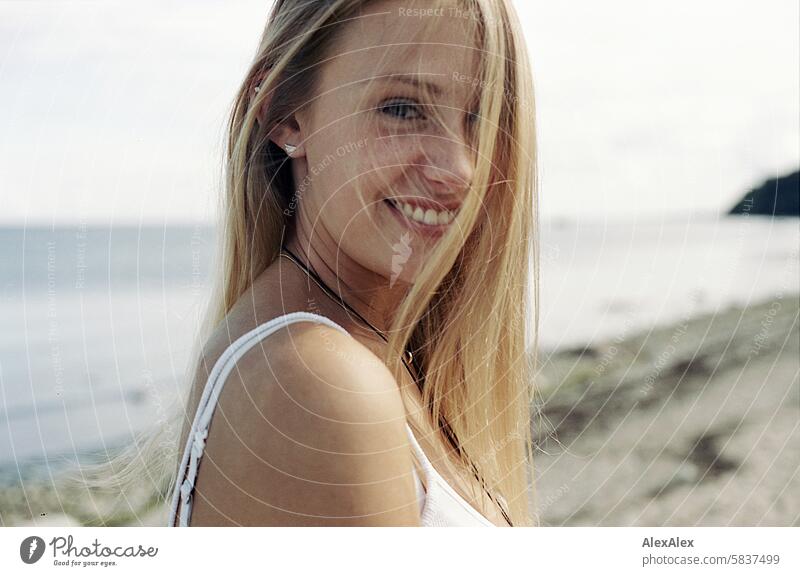 Young, blonde, tall woman smiles on the Baltic Sea beach - her long hair half hides her beautiful face Woman Girl Large 18 years Long-haired Blonde Summer