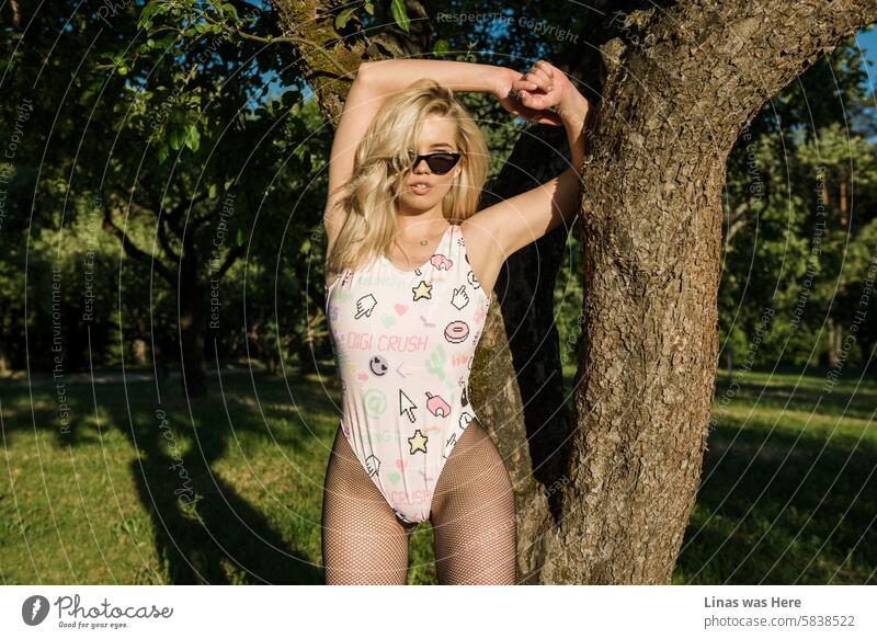 A gorgeous blonde fashion model in a pink swimsuit poses flawlessly in front of the camera. She’s wearing sunglasses and looks exactly like the legendary Claudia Schiffer. Or is it?