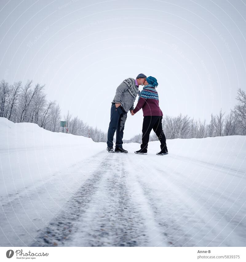 an elderly couple in knitted Icelandic sweaters making out on a street in Finnish Lapland in winter Couple Kissing Winter Street Cold older people older couple