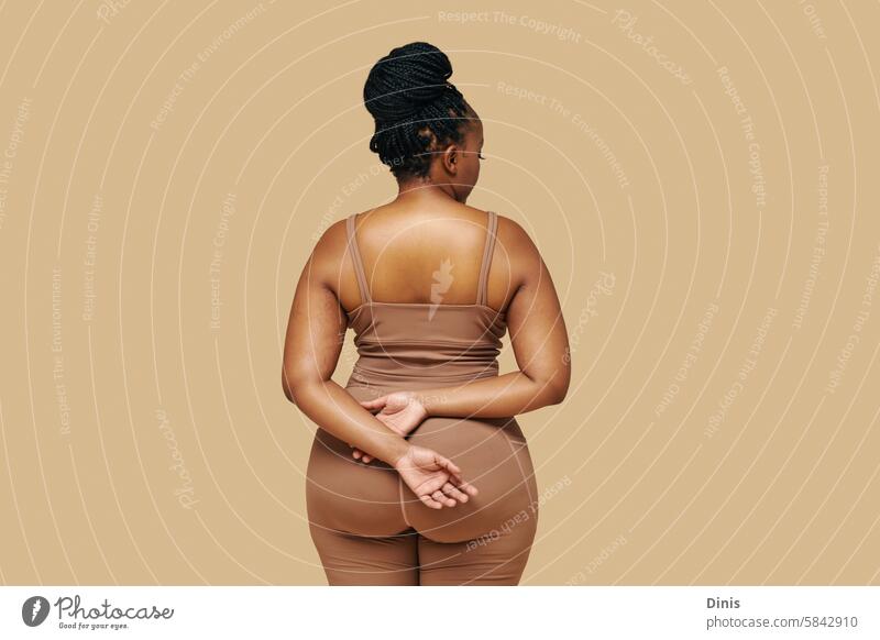 Studio portrait of curvy Black woman in sportswear, view from the back dysmorphia disordered self-acceptance appearance African American female butt figure