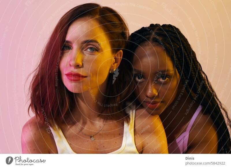 Portrait of beautiful Black and Caucasian women standing in neon light female beauty appearance best friend Party woman confidence portrait various wellbeing