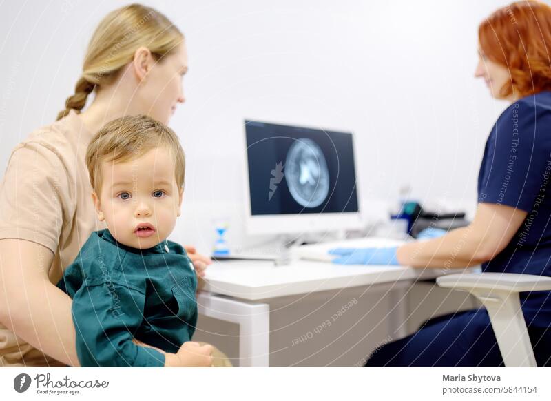 Toddler boy with his mom are at appointment with a pediatric neurologist. A mother tells an attentive doctor about her baby's injury. pediatrician brain x-ray