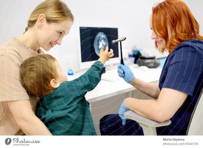 Baby and his mother are being seen by a pediatric neurologist in a modern medical clinic. Doctor conducts tests, checks the reflexes using neurological hammer of small patient. Highly qualified cure