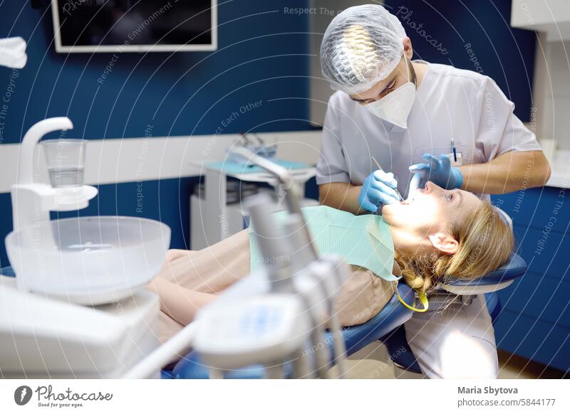 Dentist and patient at modern medical center. Doctor treats a young woman teeth in hospital. Practitioner examines the patient before orthodontists or prosthetics treatment.