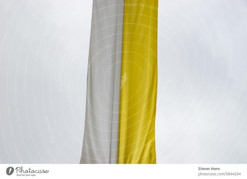 Catholic banner flag in yellow and white division against a gray sky Banner flag Flag yellow-white Church Symbols and metaphors grey sky symbol religion Drapery