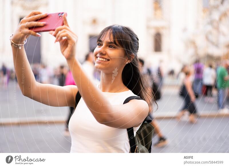 Happy teen girl with backpack taking a selfie in Rome square on vacation phone smile happy beautiful cheerful tourist travel fun joy cute camera photography