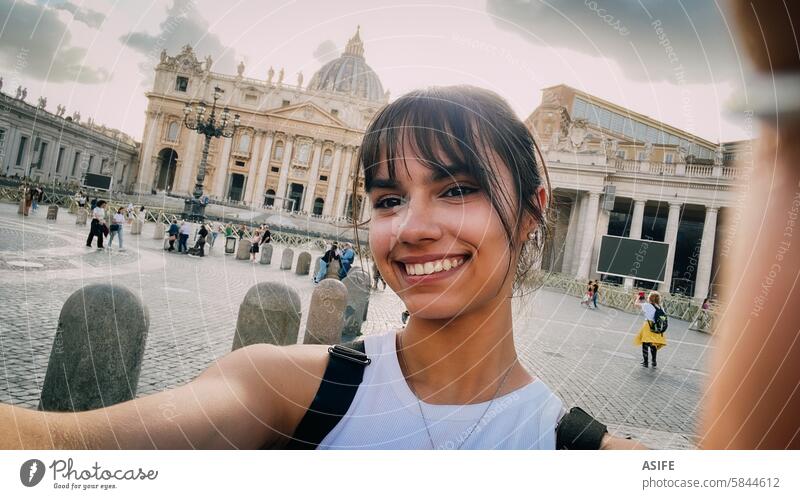 Selfie of a happy girl in front of Saint Peter basilica in Rome on vacation selfie teen phone smile Vatican student square monument beautiful cheerful tourist