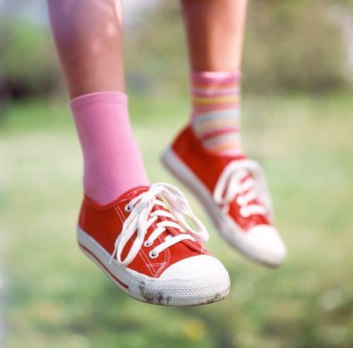 I sit here on my tree... Sneakers Footwear Red Stockings Striped socks Difference Shoelace Pink Calf Meadow Grass Exterior shot Depth of field Child Girl