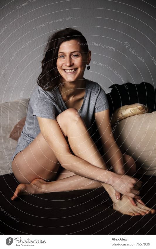 young athletic woman with long legs sits barefoot on couch and smiles Living room Sofa Cushion Young woman Youth (Young adults) Face Legs Barefoot 18 - 30 years