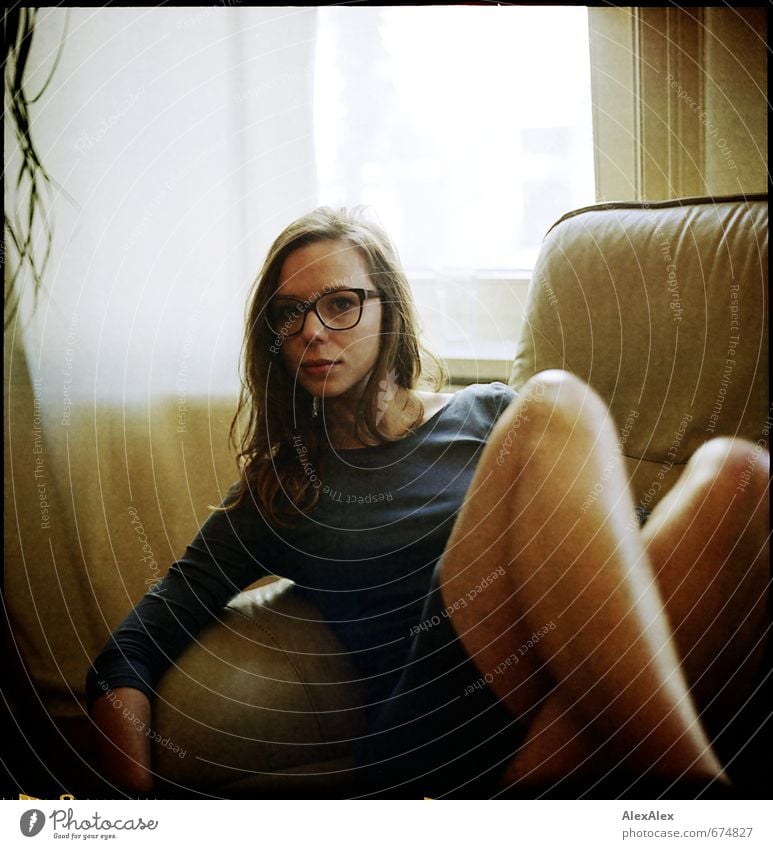 active Armchair Living room Young woman Youth (Young adults) Face Legs Eyeglasses 18 - 30 years Adults Dress Brunette Long-haired Observe Crouch Looking Sit