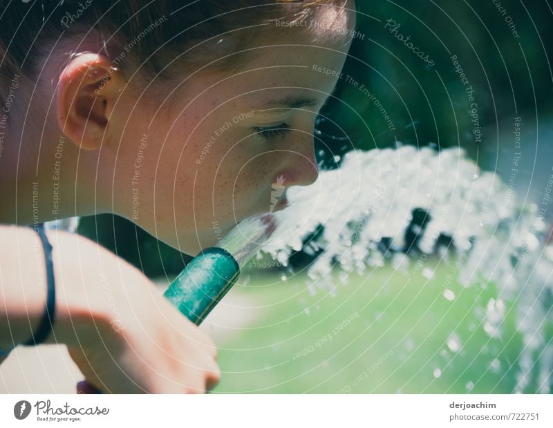 A girl is holding a water hose in her hand. She is drinking from the water that flows out of it. Quench. Drinking Well-being Summer Feminine Girl Mouth 1