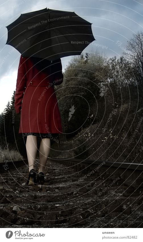 let it go Woman Adults Legs Nature Sky Clouds Tree Railroad tracks Coat Umbrella Going Red Loneliness To go for a walk Colour photo Subdued colour Exterior shot
