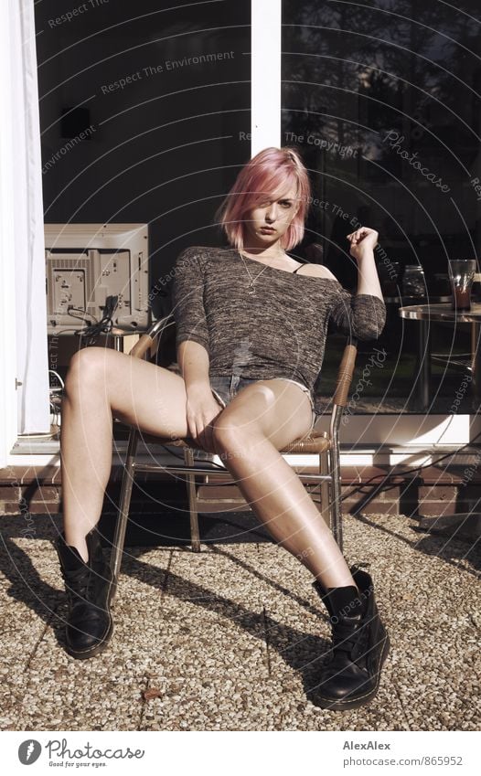Portrait of a long legged, slim woman with pink hair sitting on a chair outside on the terrace Young woman Youth (Young adults) Legs 18 - 30 years Adults
