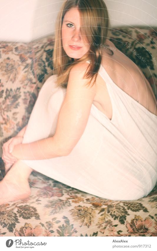 Young woman in undershirt sitting on a flowered couch and looking sideways into the camera Sofa Room Night life Youth (Young adults) Face Back Freckles