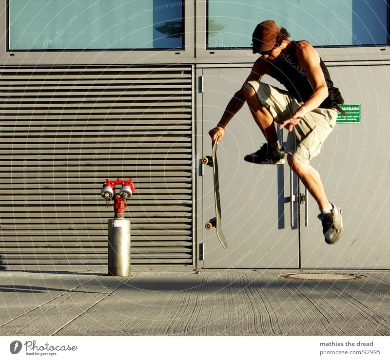 Flight phase I Sports Burden Healthy Leisure and hobbies Jump Skateboarding Fire hydrant Red Concrete Wall (building) Sunlight Man Young man Cap Shorts