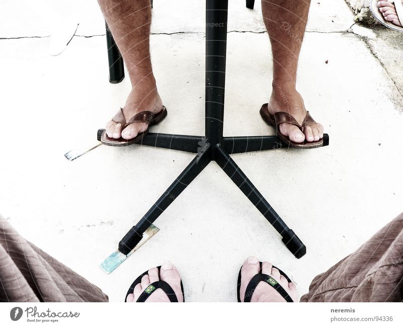 cooperation Colour photo Exterior shot Close-up Day Summer Table Man Adults Legs Feet 2 Human being Pants Flip-flops Stone Communicate Sit Firm Brown Gray White