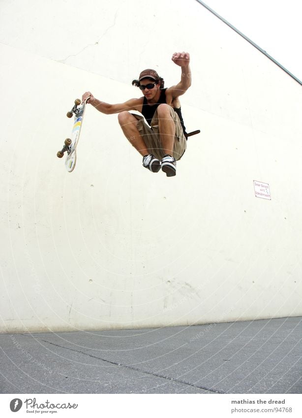 flight attempt Sports Burden Healthy Leisure and hobbies Jump Skateboarding Concrete Wall (building) Light Sunlight Man Young man Cap Shorts Jumping power