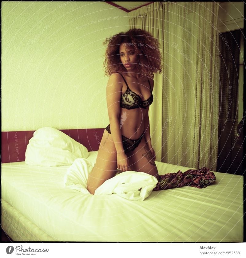 analogue portrait of a young, dark-skinned woman, dressed in lingerie, kneeling on a hotel bed and looking to the side Adventure Bed Night life Young woman