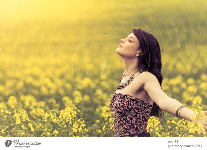 Beautiful young woman in summer in a sea of yellow rape to the horizon. Pretty girl with zest for life enjoying the sunshine break and life. Rest and recharge energy from time environment stress in nature idyll.