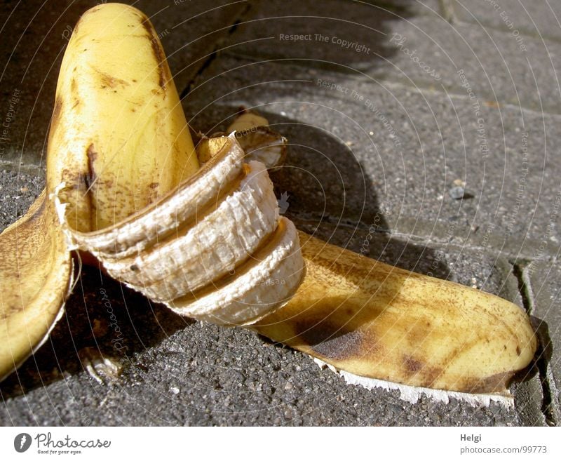 Discarded banana skin lying on a sidewalk Banana Yellow Brown Dappled Eaten Empty White Sidewalk Accident Risk of accident Throw away Shackled Trash